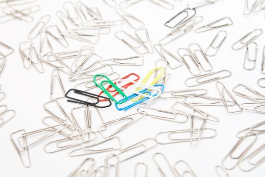 Five colourful paperclips among many steel grey paperclips on white background