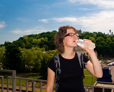 Young woman walking in the city and refreshing herself with cold fresh water