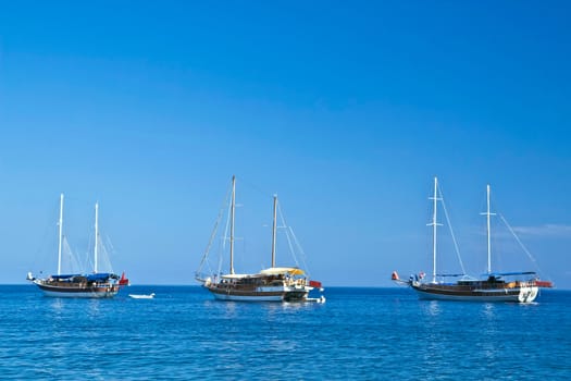 three sailboats with lowered sails in sunny weather