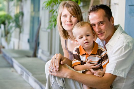 Happy perfect young family with dad, mom and son outdoors having fun