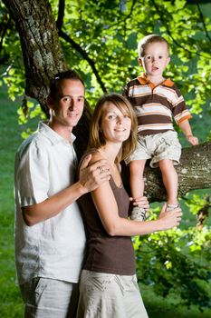 Happy perfect young family with dad, mom and son outdoors having fun