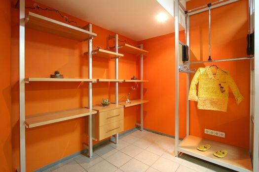 Wardrobe room with orange walls and regiments for clothes