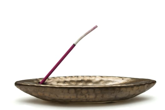 a pink incense in a holder on a white background