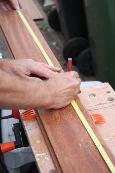 A Carpenter measuring wood in order to saw