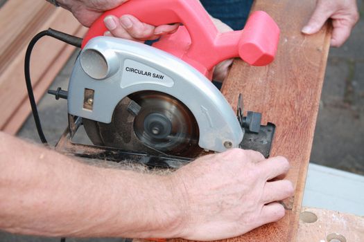 construction worker cutting wood with circular saw