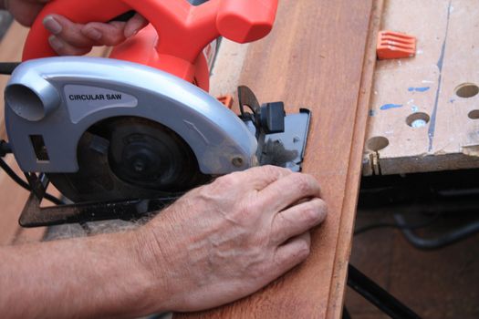 construction worker cutting wood with circular saw