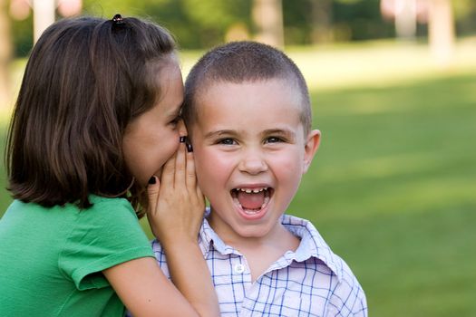 A young girl telling her brother a secret.