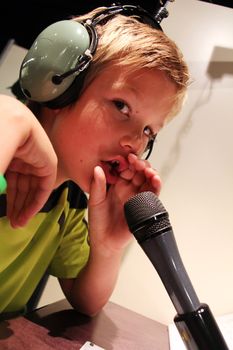 young boy with headphone and microphone is speaking