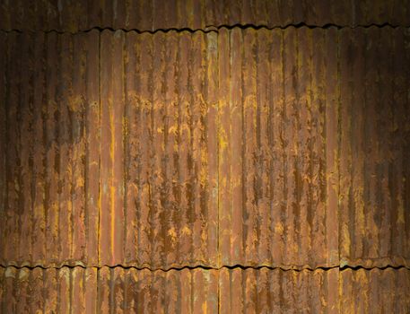 Corroded and rusty corrugated metal roof panels lit dramatically