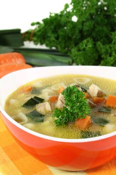 Chicken soup with vegetables and parsley in a bowl