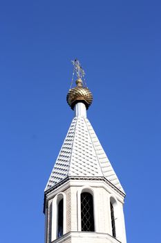 Golden dome of the Orthodox church in Central Russia on the blue sky background partially covered with snow. 