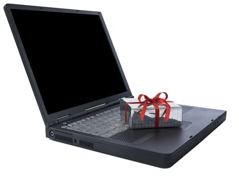 Small gift wrapped with a red ribbon over a black laptop isolated on white. Black copy space on screen.