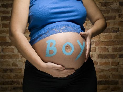 Pregnant woman with the word BOY written in her belly.