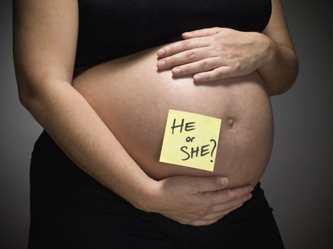 Pregnant woman with the question HE or SHE? written in her belly.