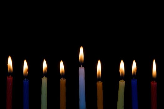 9 Hanukah Candles burn, isolated on black