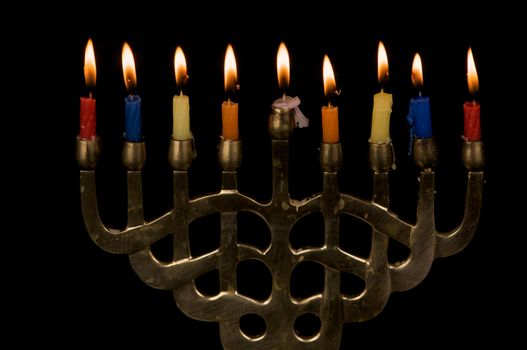 A gold colored menorak with lit Hanukah candles