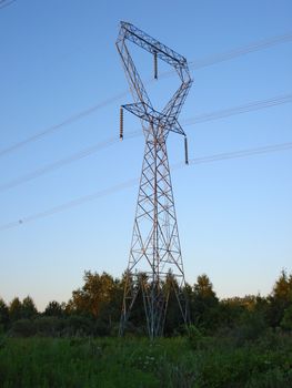 A tower holding the power lines against a blue sky.