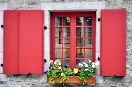 Old window with colorful flowers in Quebec City, Canada.