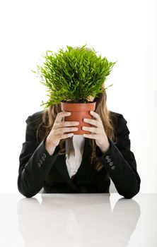 Portrait of a young and beautiful businesswoman hiding behind a plant