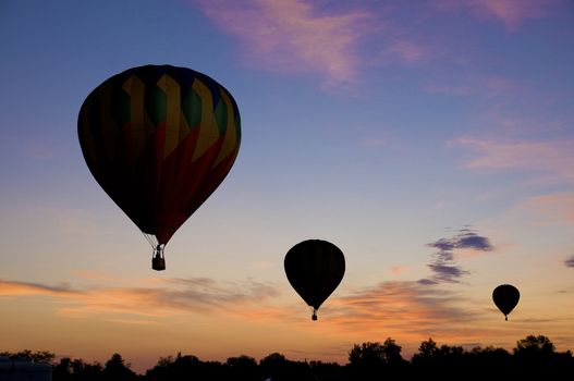 Hot-air balloons floating against a reddish dawn or dusk sky