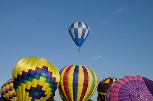 Hot-air balloon ascending over other inflating ones on the ground