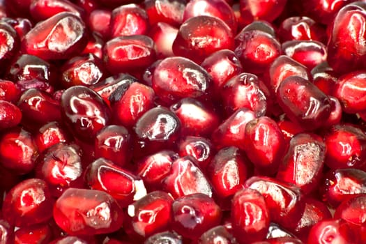 Extreme close up background of a red juicy ripe pomegranate fruit seeds 