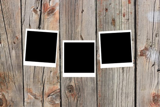 set of three old blank polaroids frames lying on a wood surface 