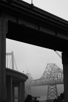 Two tall modern bridges in a fog.