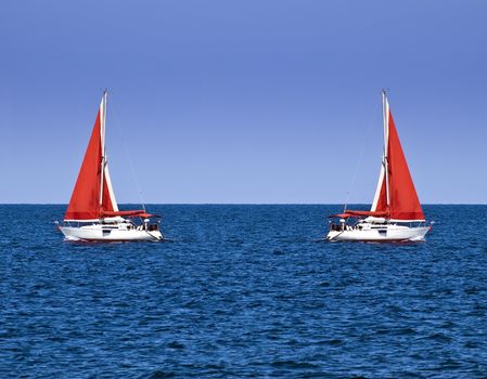 Yacht with a red sail offering crisp contrast against sky and ocean blue