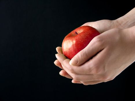 Red Apple in hands on black background