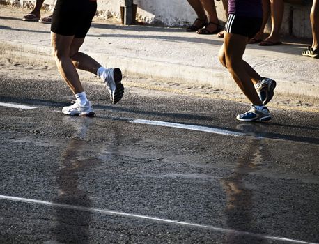 Detail of two joggers' feet running down the coastline at Mellieha Bay