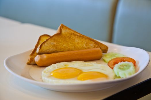 fried eggs, sausage, toast, and vegetables on white plate