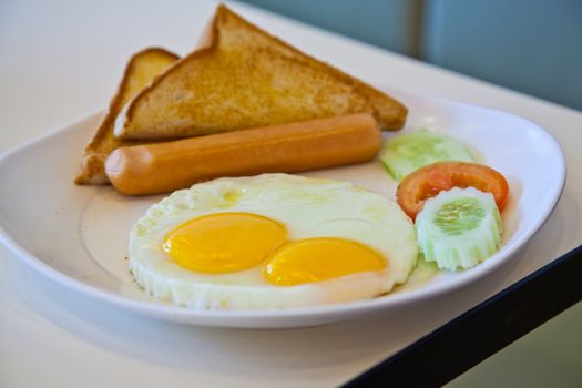 fried eggs, sausage, toast, and vegetables on white plate