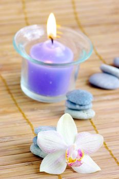 spa concept with candles orchids towels and stones on wet wooden background