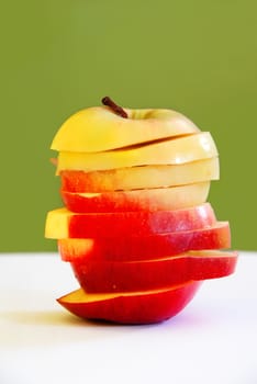 yellow red apple slices in long apple shape over green