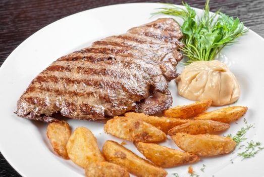 Juicy beef steak stuffed with beef tongue and cheese served with potatoes, greenery and sauce