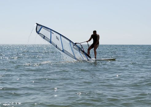 Windsurfer heaving a sail among the waves