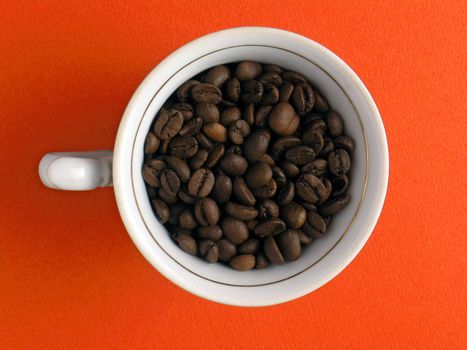 Cup of coffe-beans on orange background