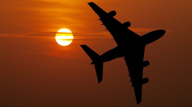 Large airliner flying over a beautiful  red sunset