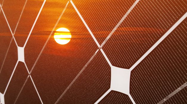 Renewable energy concept with photovoltaic panel and red sun