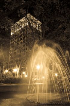 A fountain in the middle of a city park at night