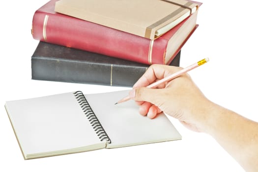 hand writing with pencil on, cream colored paper notebook and book as background