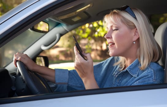 Attractive Blonde Woman Text Messaging on Her Cell Phone While Driving.