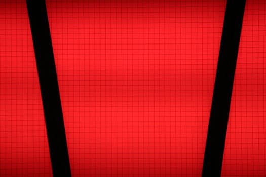 Close-up of red glass lit from behind. This safety glass has a very fine wire netting inside, which makes a grid of squares. Suited as background image.