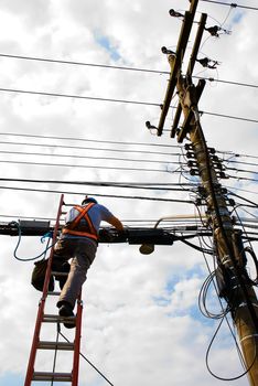 Unrecognisable utility worker (from behind) with electrical cables in the background.