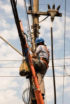 Unrecognisable of utility worker (from the side) with electrical cables in the background.