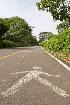 Perspective shot of a road with a pedestrian symbol painted on it.
