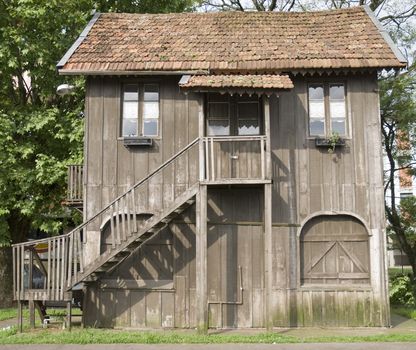 Front shot of an old-style wooden house with two floors and wooden staircase