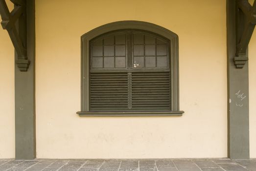 Front shot of a rustic brown wooden window, with cream coloured wall.