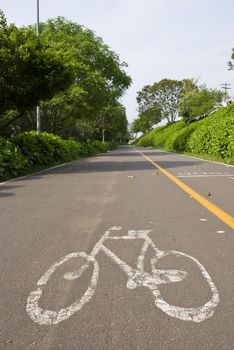 Perspective shot of a road with a bicycle symbol painted on it.